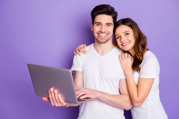 Photo pretty lady handsome guy couple good mood hold notebook hands watch movie film together spend free time leisure wear casual white t-shirts isolated purple pastel color background - 写真・画像