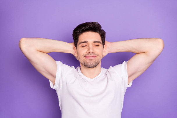 Photo of attractive handsome guy good mood arms behind head eyes closed dreamer creative person inspiration flight wear casual white t-shirt isolated purple pastel color background - Valokuva, kuva