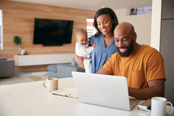 自宅で財務をチェックするためにラップトップを使用して赤ちゃんの娘とアフリカ系アメリカ人の家族 - 写真・画像