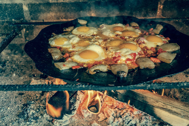 Œuf brouillé frit sur les charbons dans une casserole sur feu ouvert, cuire sur un feu ouvert. Les œufs sont frits sur un feu. - Photo, image