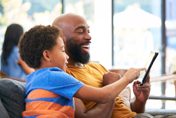 African American Family At Home With Father And Son Sitting On Sofa At Home Using Digital Tablet - Photo, Image