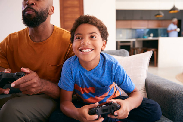 African American Father And Son Sitting On Sofa At Home Playing Video Game Together - Zdjęcie, obraz