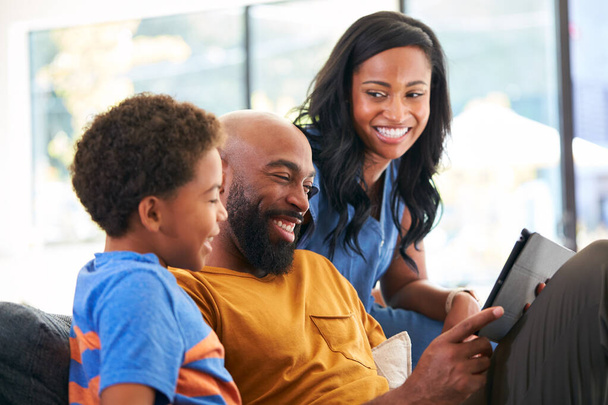 African American Family With Son Sitting On Sofa At Home Using Digital Tablet - Foto, Imagem