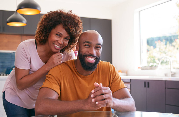 Portrait de sourire afro-américain fils adulte avec mère dans la cuisine à la maison - Photo, image