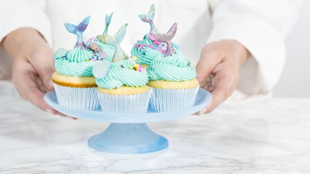 Step by step. Arranging mermaid vanilla cupcakes with chocolate mermaid tails on a cupcake stand. - Fotografie, Obrázek