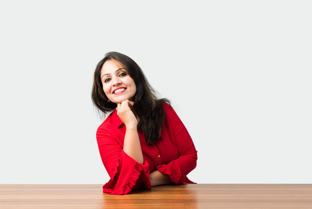 Індійська вродлива жінка, що стоїть за столом і тримає підборіддя на руках. - Фото, зображення