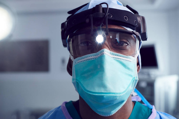 Portrait Of Male Surgeon Wearing Protective Glasses And Head Light In Hospital Operating Theater - Fotoğraf, Görsel