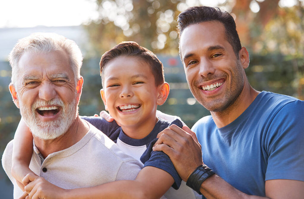 Portrait Of Multi-Generation Male Hispanic Family In Garden Smiling At Camera - Фото, изображение