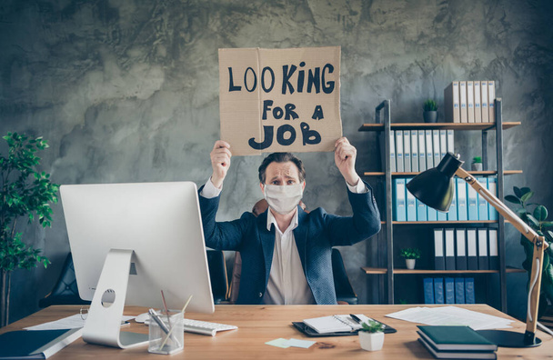 Photo of fired depressed miserable agent guy holding in hands promo placard looking new chance job at loft industrial workplace - Fotoğraf, Görsel
