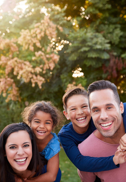 Portrait Of Smiling Hispanic Family With Parents Giving Children Piggyback Rides In Garden At Home - Fotó, kép