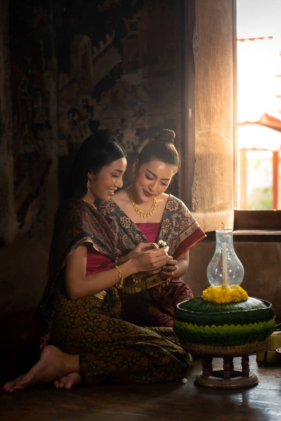 Zwei Thailänderinnen in traditioneller Tracht, die Krathong herstellen und dekorieren. Loy Krathong Festival. - Foto, Bild