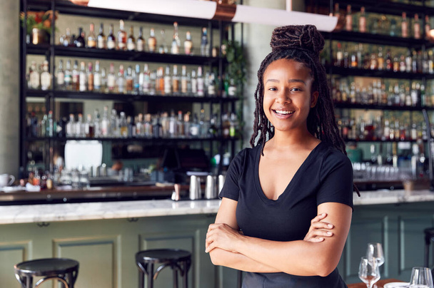 Portrait Of Confident Female Owner Of Restaurant Bar Standing By Counter - Foto, imagen
