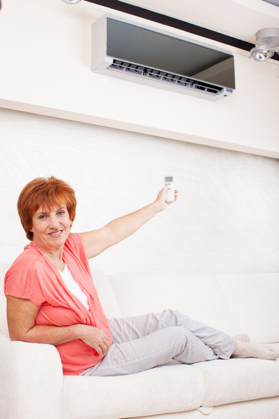 Woman holding a remote control air conditioner - Fotó, kép