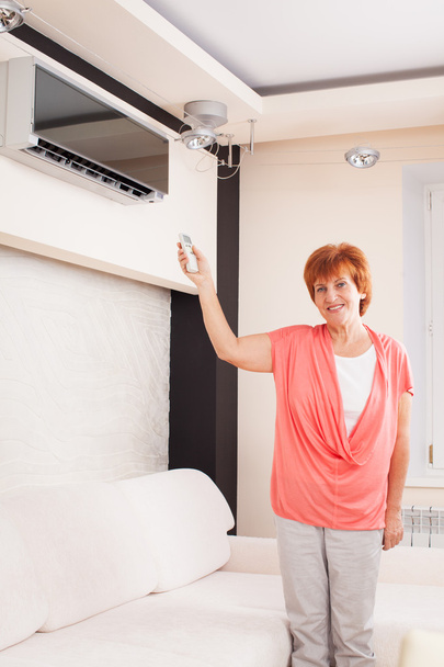 Woman holding a remote control air conditioner - Valokuva, kuva
