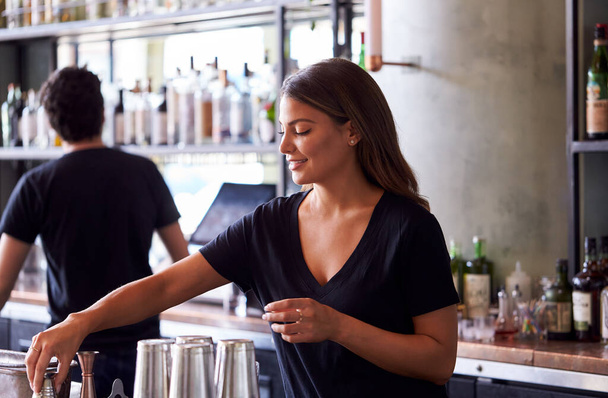 Female Bartender Mixing Ingredients For Cocktail Behind Bar - Foto, Imagen