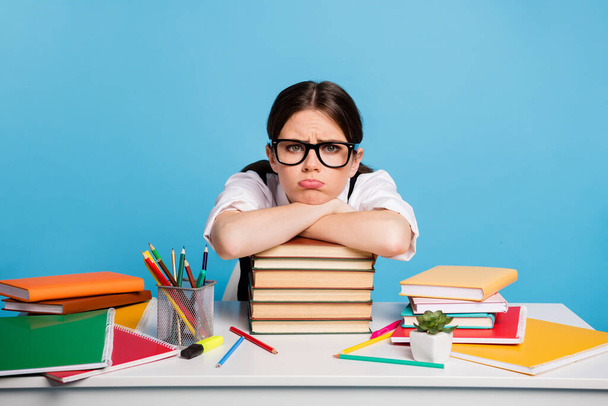 Photo of frustrated university student girl sit table put hands head pile stack copybook dislike many graduate homework wear white blouse black uniform isolated blue color background - Fotoğraf, Görsel