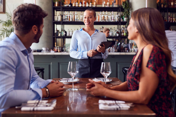 Garçonete feminina com tablet digital tomando ordem de casal romântico sentado na mesa do restaurante - Foto, Imagem