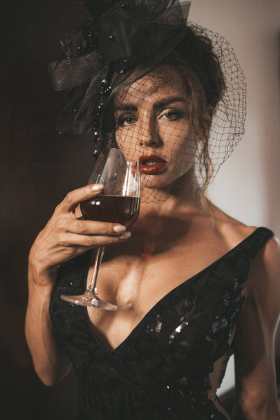 Elegante vrouw in een zwarte jurk in het hotel. Retrostijl - Foto, afbeelding
