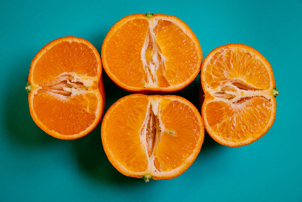 Color pop. Cuatro rebanadas de mandarina naranja sobre un fondo azul. Concepto de comida. Mínimo. - Foto, imagen