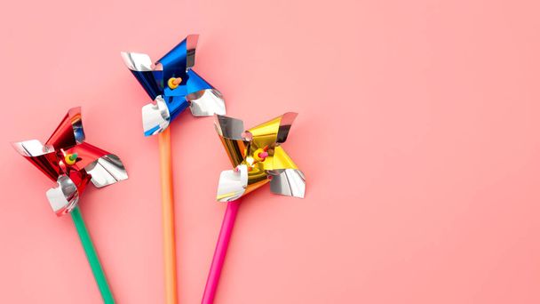 黄色、青、赤のプラスチック製のおもちゃの風車やコピースペースとピンクの背景に隔離されたピンホイールとレトロゲームやヴィンテージのおもちゃのコンセプト - 写真・画像