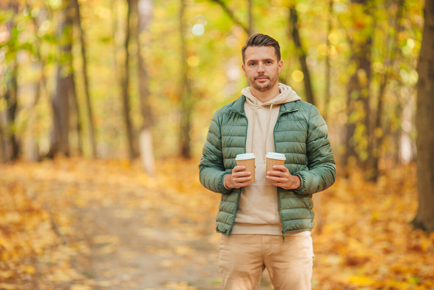 Young man drinking coffee in autumn park outdoors - Foto, Imagen