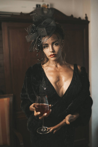 Elegant woman wearing black dress in hotel. Retro style - Foto, afbeelding