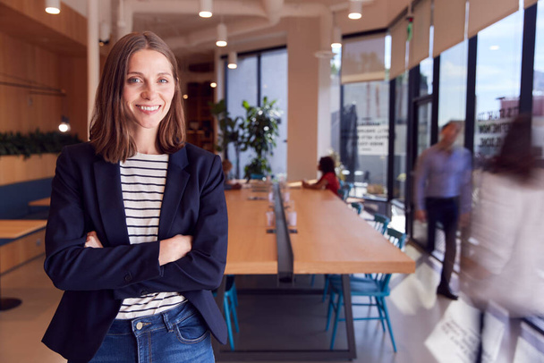 Portrait Of Businesswoman Standing In Busy Modern Open Plan Office  With Colleagues In Background - Foto, Imagen