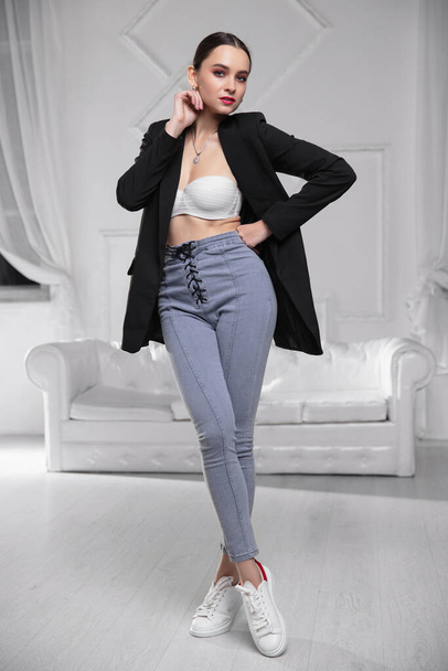 Lovely woman wearing a jacket, bra and jeans posing in the studio - Fotografie, Obrázek