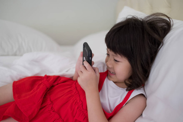 kid is addicted to tablet, little girl playing smartphone, kid use telephone, watching cartoon - Foto, Imagem