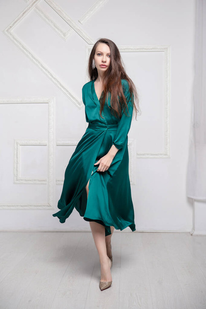 Stüdyoda poz veren yeşil ipek elbiseli güzel bir esmer. - Fotoğraf, Görsel