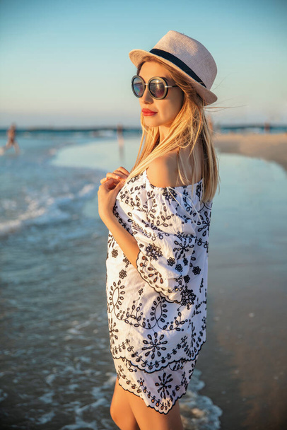 Kauniin naisen muotokuva Välimeren taustalla, yllään tunika, lasit ja hattu. - Valokuva, kuva