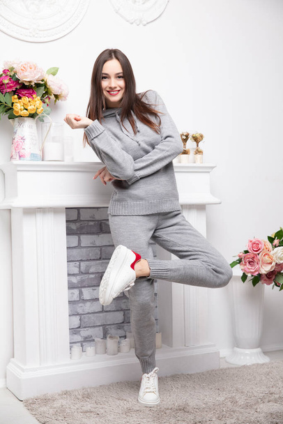 Smile brunette dressed in a gray suit posing near the fireplace - Photo, image