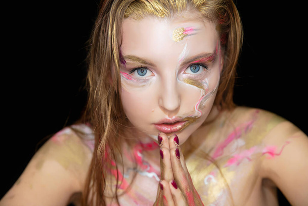 Portret van een mooie jonge vrouw met creatieve make-up op haar gezicht - Foto, afbeelding