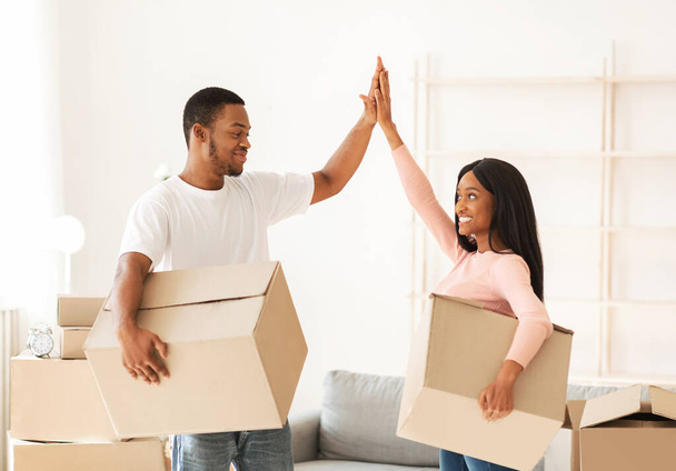 Jeune couple noir avec des boîtes en carton haut de cinq dans leur propriété louée le jour du déménagement - Photo, image