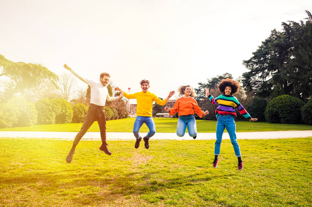 Podekscytowana grupa dla przyjaciół czujących się swobodnie skacząc na zewnątrz podświetlenie zabawy razem świętując sukces  - Zdjęcie, obraz