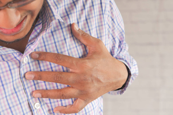 mladý muž trpí bolestí srdce a drží hrudník s rukou  - Fotografie, Obrázek