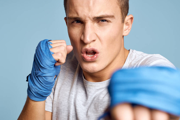 sporty man in blue boxing gloves and t-shirt on blue background practicing punches cropped view - Foto, immagini