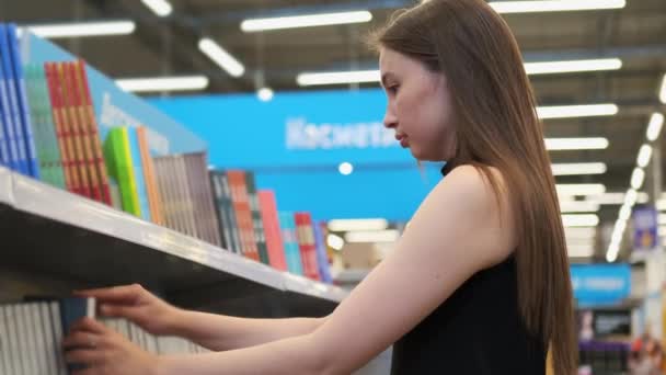 Mujer joven está comprando un libro en una tienda - Metraje, vídeo