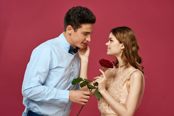 portret van romantisch paar in liefde met rode roos op geïsoleerde achtergrond en klassieke pak avondjurk - Foto, afbeelding