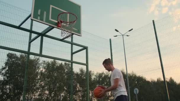 αθλητής ρίχνει μπάλα στο καλάθι σε ανοικτό γήπεδο streetball - Πλάνα, βίντεο