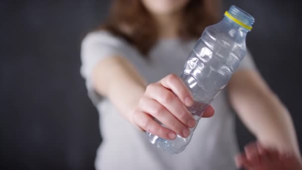 Primer plano de sección media de la botella de agua de plástico en enfoque selectivo y joven activista que la arruga para un ambiente claro - Metraje, vídeo