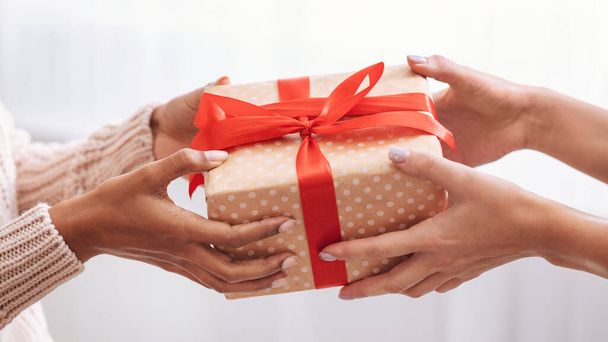 Female hands holding and giving present box to woman - Фото, изображение