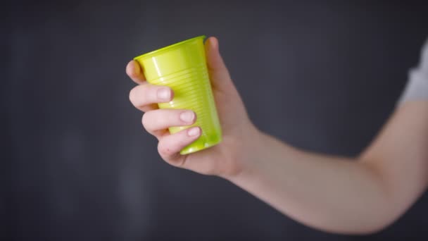Close-up van bijgesneden vrouwelijke handen verkruimelen wegwerp plastic beker op donkere achtergrond - Video