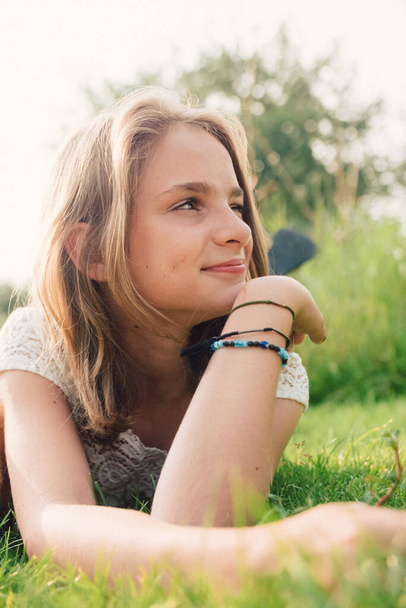 Jeune adolescente dans une robe blanche posée dans l'herbe au soleil d'été. - Photo, image