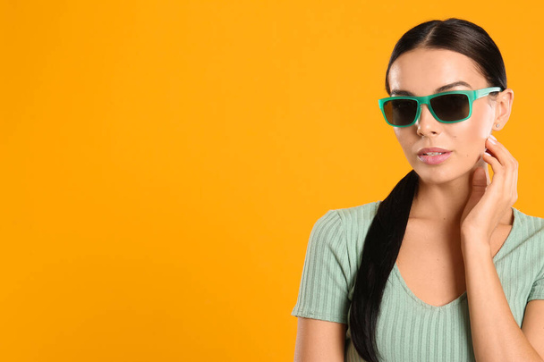 Beautiful woman wearing sunglasses on yellow background. Space for text - Fotó, kép