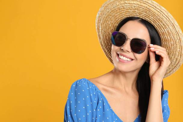 Beautiful woman wearing sunglasses on yellow background. Space for text - Zdjęcie, obraz