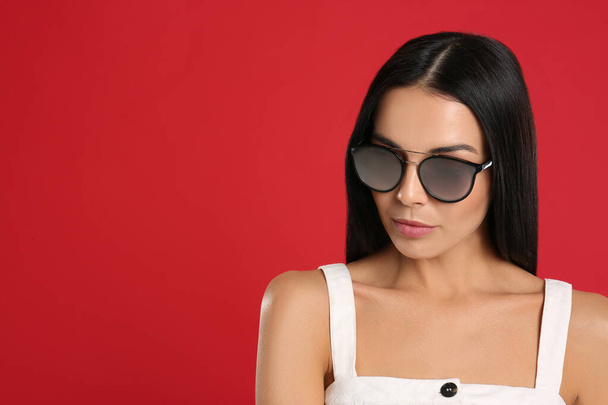 Beautiful woman wearing sunglasses on red background. Space for text - Фото, зображення