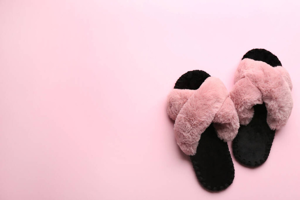 Pair of soft slippers on light pink background, flat lay. Space for text - Фото, изображение