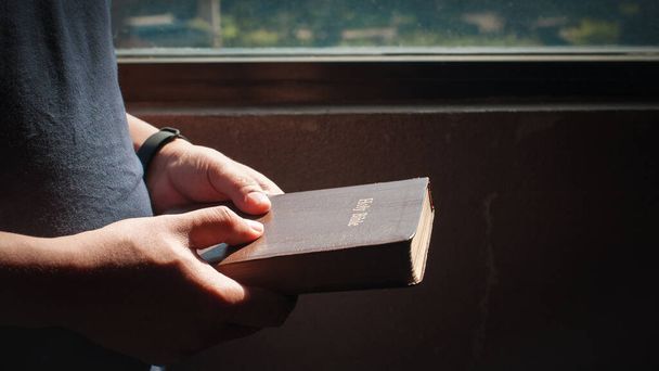 Szent Biblia, tinédzser ember kezében a Szent Biblia készen áll az olvasásra és az imádságra, hogy kapcsolatban legyen Isten hit, spiritualitás, és a vallás fogalma. - Fotó, kép