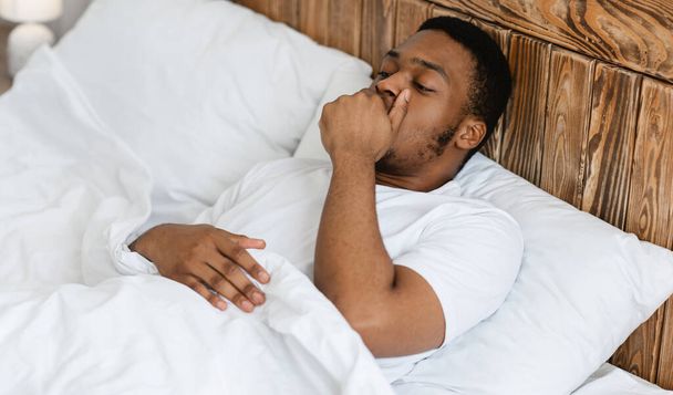 Sleepy Black Man Yawning Awakening Lying In Bed At Home - Foto, imagen